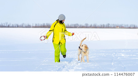 Girl with cute young retriever dog on winter walk 114476007