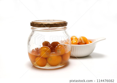 Honey-pickled kumquats in a glass jar 114476082