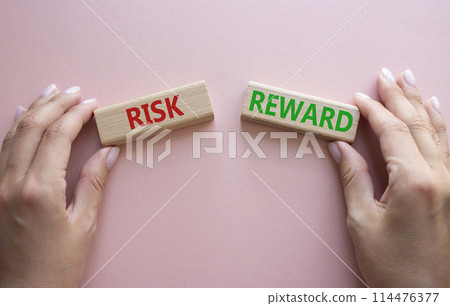 Risk or Reward symbol. Concept word Risk or Reward on wooden blocks. Businessman hand. Beautiful pink background. Business and Risk or Reward concept. Copy space Risk or Reward symbol. Concept word Risk or Reward on wooden blocks. Businessman hand. Beautiful pink background. Business and Risk or Reward concept. Copy space 114476377