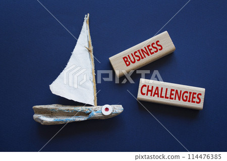 Business challenges symbol. Concept word Business challenges on wooden blocks. Beautiful deep blue background with boat. Business and Business challenges concept. Copy space Business challenges symbol. Concept word Business challenges on wooden blocks. Beautiful deep blue background with boat. Business and Business challenges concept. Copy space 114476385