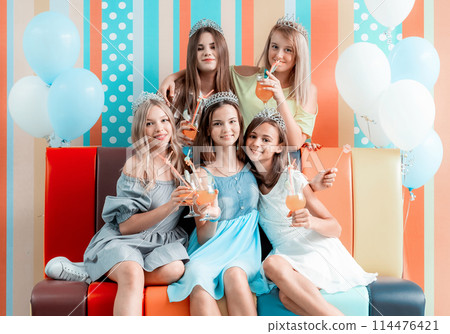 Cheerful teenage girls at birthday party with cocktails and ballons Cheerful teenage girls at birthday party with cocktails and ballons 114476421