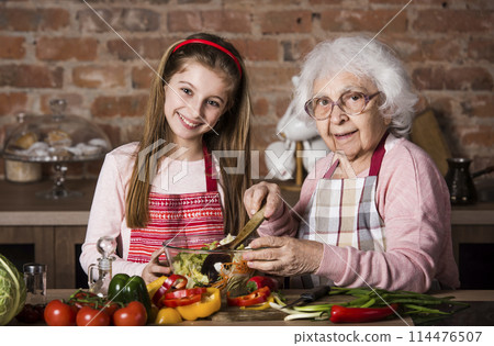 Grandmother and cute granddaughter cooking healthy food at home at kitchen 114476507