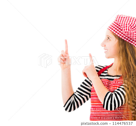 Girl in red kitchen apron and chef hat pointing up isolated on white background 114476537