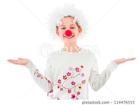 Cute teen girl in white clown wig and big red nose showing two empty palms and looking at camera isolated on white background. Copyspace Cute teen girl in white clown wig and big red nose showing two empty palms and looking at camera isolated on white background. Copyspace 114476555