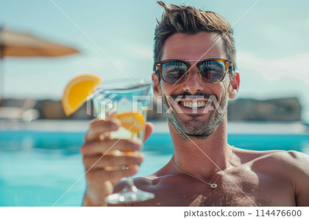 Man holds a glass with a cocktail on the background of the pool 114476600