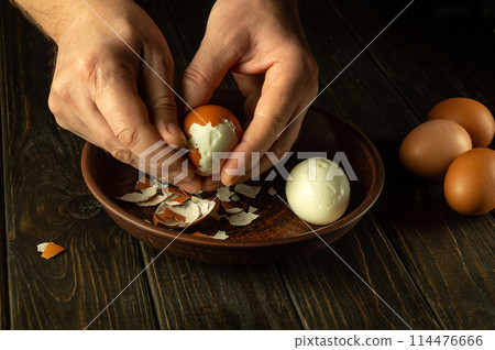 Hands peel an egg. Chef hands peeling boiled eggs on the kitchen table before preparing breakfast 114476666
