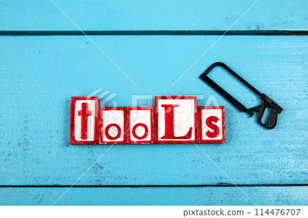 TOOLS. Miniature saw on a blue wooden background. Construction and carpentry concept TOOLS. Miniature saw on a blue wooden background. Construction and carpentry concept 114476707