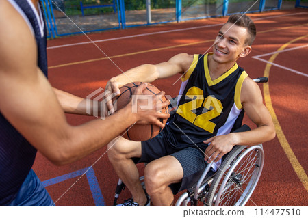 Wheelchair basketball player on court playing with friend 114477510