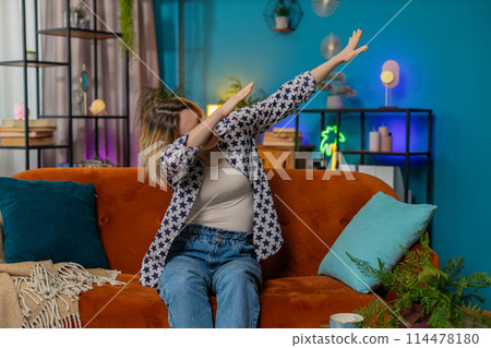 Trendy cheerful positive woman having fun dancing dabbing raising hands making dub winner dance 114478180