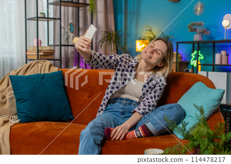 Happy young woman making online video call conversation on smartphone talking waving hand hello Happy young woman making online video call conversation on smartphone talking waving hand hello 114478217