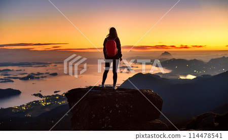 Woman watching the sunrise from the top of a mountain 114478541