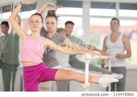 Teen ballet students prepare for classes, near ballet bare stretch legs under man teacher guidance 114478968