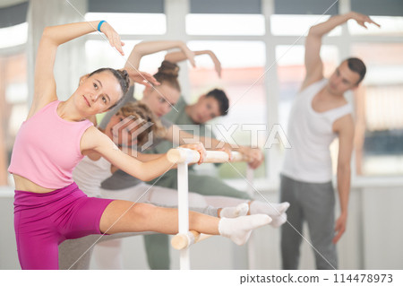 Teen ballet students prepare for classes, near ballet bare stretch legs under man teacher guidance 114478973