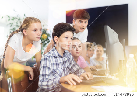 Preteen boys and girls working on computer together with teacher in IT cabinet Preteen boys and girls working on computer together with teacher in IT cabinet 114478989