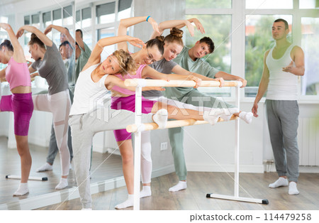 Teenage boys and girls practicing leg stretching exercise during ballet classes Teenage boys and girls practicing leg stretching exercise during ballet classes 114479258