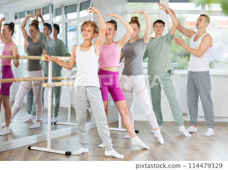 Teenage boys and girls practicing battement tendu position of ballet in dancehall Teenage boys and girls practicing battement tendu position of ballet in dancehall 114479329