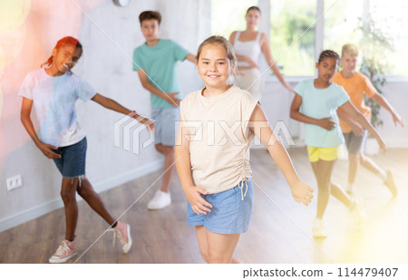 Cheerful preteen girl enjoying active dancing during group training 114479407