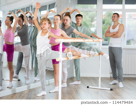 Ballet pose grand batman - girls and boys at a choreography lesson are learning ballet movements in studio Ballet pose grand batman - girls and boys at a choreography lesson are learning ballet movements in studio 114479484