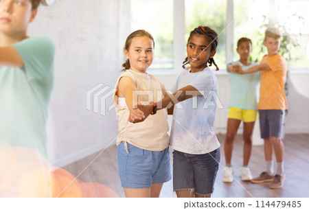 Cheerful preteen african american boy dancing slow foxtrot with smiling girl Cheerful preteen african american boy dancing slow foxtrot with smiling girl 114479485