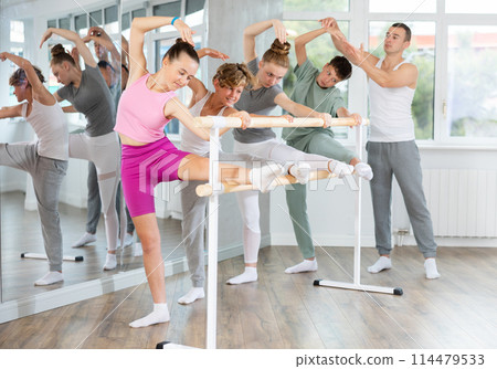 Teenage boys and girls practicing leg stretching exercise during ballet classes 114479533