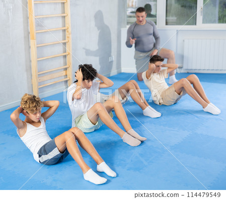 Children performing exercises to strengthen press, pump muscles of core, actively spend time in gym Children performing exercises to strengthen press, pump muscles of core, actively spend time in gym 114479549