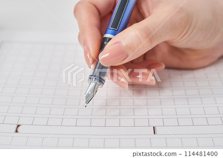 Woman's hand holding a fountain pen and manuscript paper 114481400