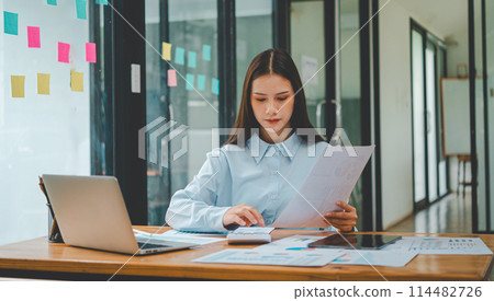 Asian business woman working using laptop for do math finance on wooden desk, tax, accounting, statistics and analytical research concept 114482726