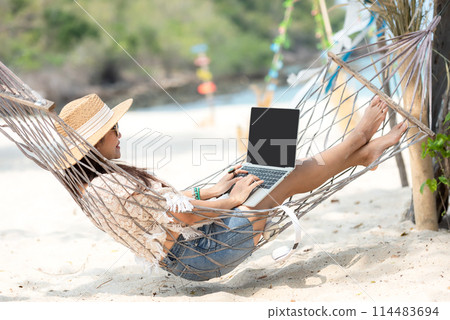Lifestyle freelance woman using laptop working and relax on the beach. Lifestyle freelance woman using laptop working and relax on the beach. 114483694