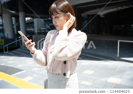 A woman looking at a smartphone in the city A woman looking at a smartphone in the city 114484025