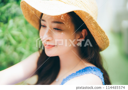 Young woman putting on a straw hat Young woman putting on a straw hat 114485574