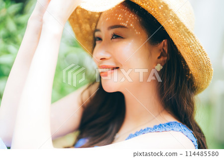 Young woman putting on a straw hat 114485580