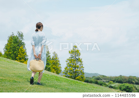 Pretty woman standing on a grassy hill 114485596