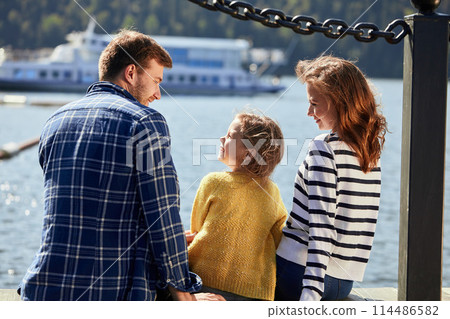 rear view of family sit on pier in autumn day. Fall family portrait rear view of family sit on pier in autumn day. Fall family portrait 114486582