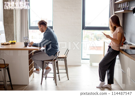 young man is looking for information for work while his wife using her mobile phone 114487547