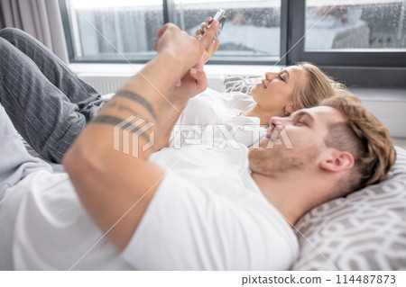 positive young couple spending time with smartphone positive young couple spending time with smartphone 114487873