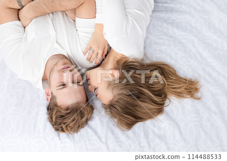 awesome girl is kissing a handsome guy while resting on the bed 114488533