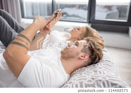Young couple with smartphones in their bed Young couple with smartphones in their bed 114488573