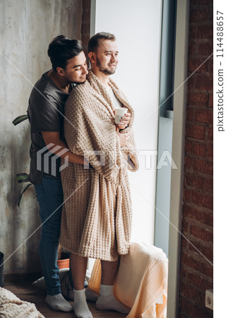 two handsome homosexual guys while standing near window two handsome homosexual guys while standing near window 114488657