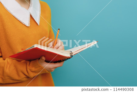 Girl with book on background of bright teal wall Girl with book on background of bright teal wall 114490308