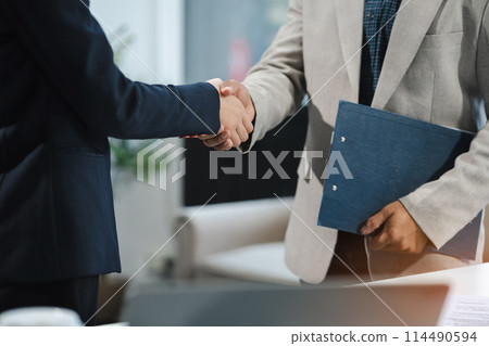 Happy businessman and businesswoman shaking hands at group board meeting. Professional business executive leaders making handshake agreement successful company trade partnership handshake concept. 114490594