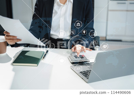 Businesswoman using a calculator to calculate the numbers of statistic business profits growth rate on documents graph data, desk in the office. 114490606