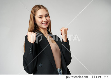 Young woman standing with her arms lifted high above her head expressing joy and triumph 114491953