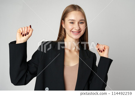 Young woman standing with her arms lifted high above her head expressing joy and triumph 114492259