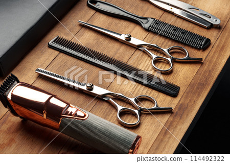 Professional Barber Tools Laid Out on Wooden Surface for Mens Grooming Session Professional Barber Tools Laid Out on Wooden Surface for Mens Grooming Session 114492322