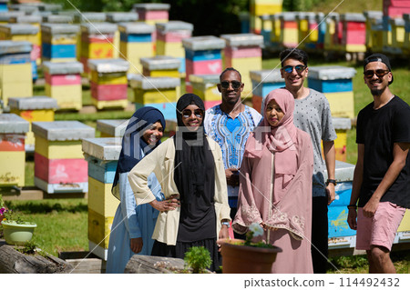A diverse group of young friends and entrepreneurs explore small honey production businesses in the natural setting of the countryside. 114492432