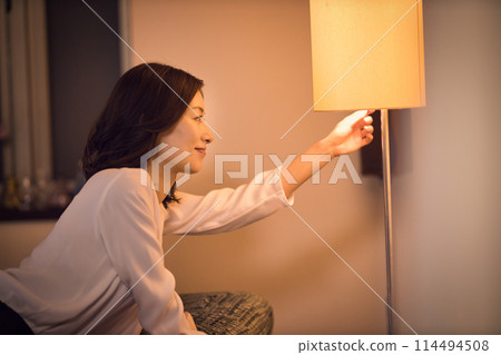 Night routine of a business woman who takes off her jacket and turns on the light at the stand. Night routine of a business woman who takes off her jacket and turns on the light at the stand. 114494508