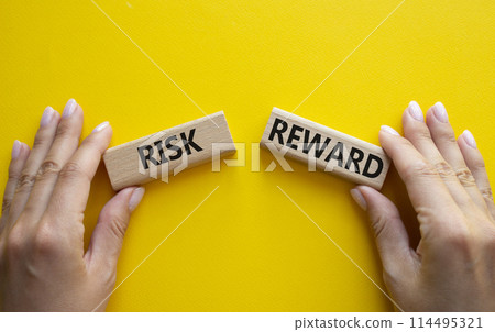 Risk or Reward symbol. Concept word Risk or Reward on wooden blocks. Businessman hand. Beautiful yellow background. Business and Risk or Reward concept. Copy space 114495321