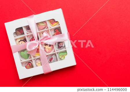 Box with sweet chocolate candies on color background, Various candy sweets. Valentines day gift box. Top view flat lay with copy space 114496000