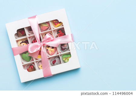 Box with sweet chocolate candies on color background, Various candy sweets. Valentines day gift box. Top view flat lay with copy space Box with sweet chocolate candies on color background, Various candy sweets. Valentines day gift box. Top view flat lay with copy space 114496004