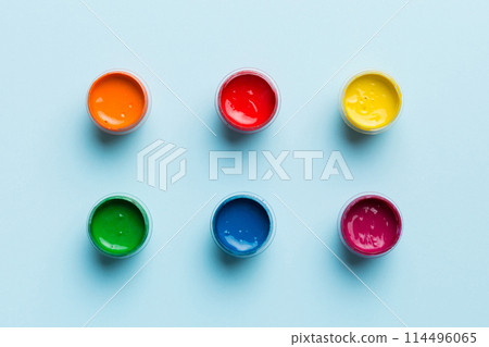 jars with gouache of different colors on Colored background. hobby painting. Top view with empty space. workplace for creativity. home teaching concept drawing 114496065